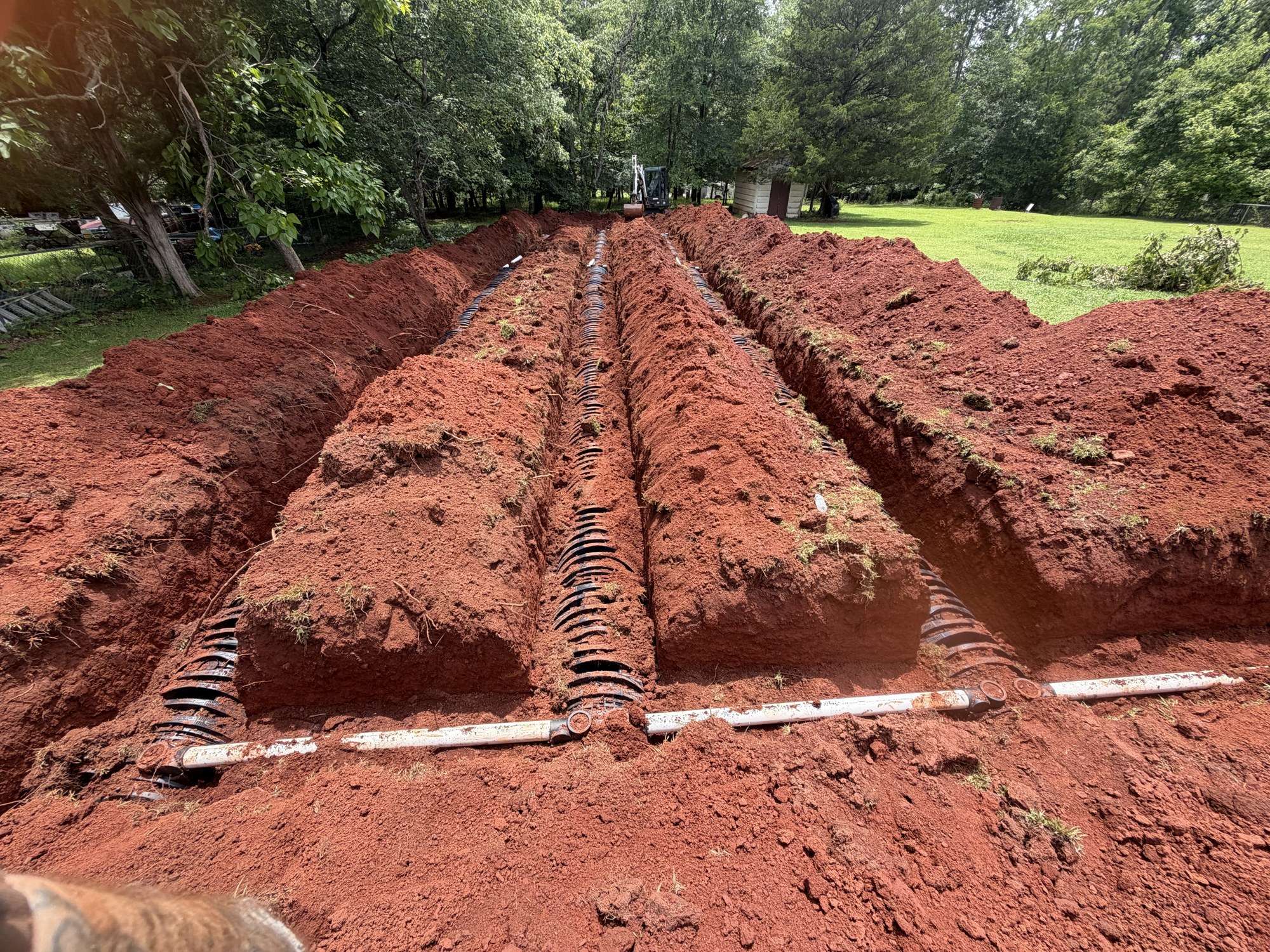 New drain field trenches cut in red Georgia clay with chambers laid in